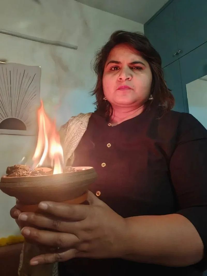 Neha Singla holding a diya during a healing ritual